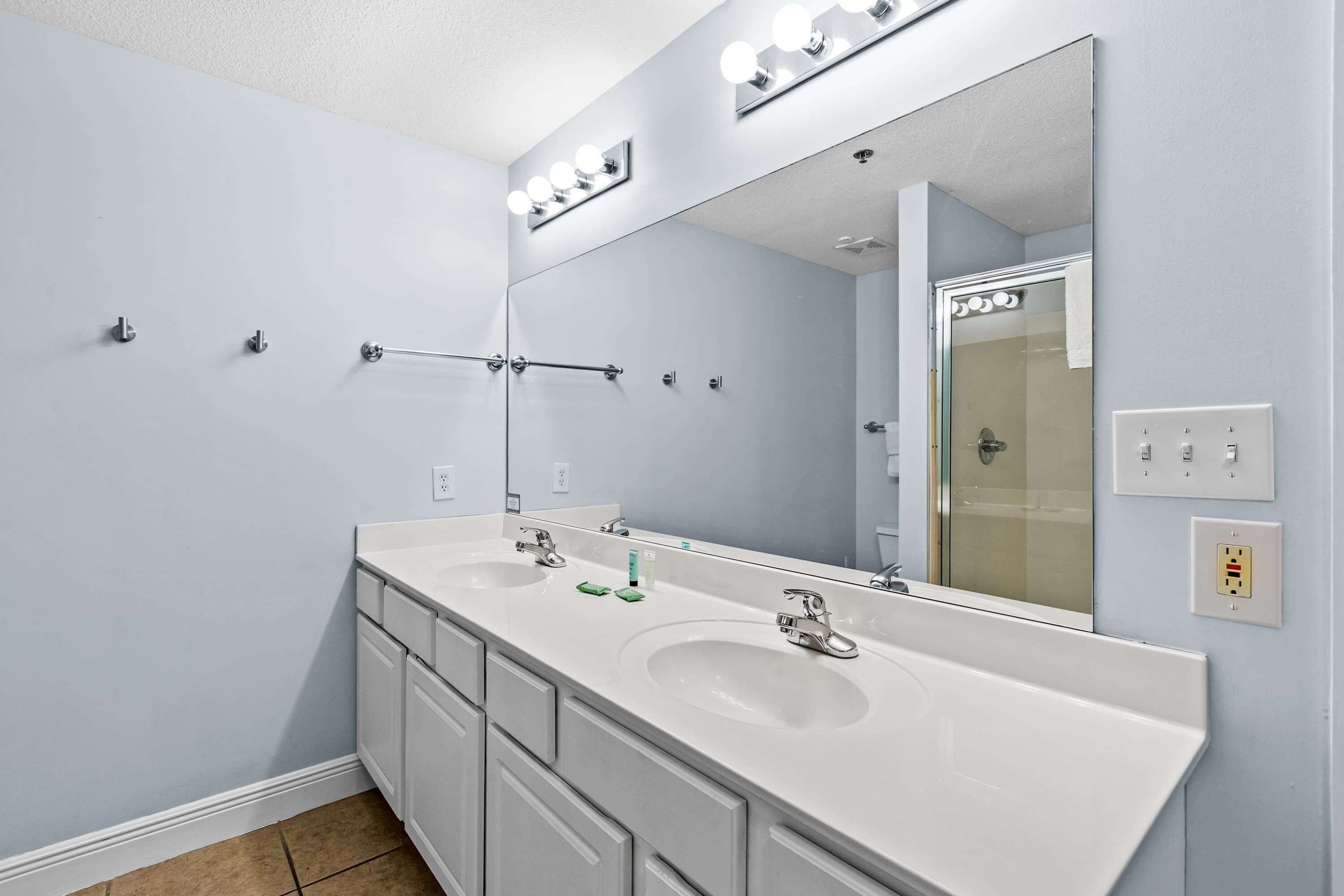 A bathroom with two sinks, a large mirror, and a towel rack.