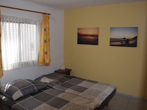 Un dormitorio con cama, cortinas y dos cuadros en la pared.