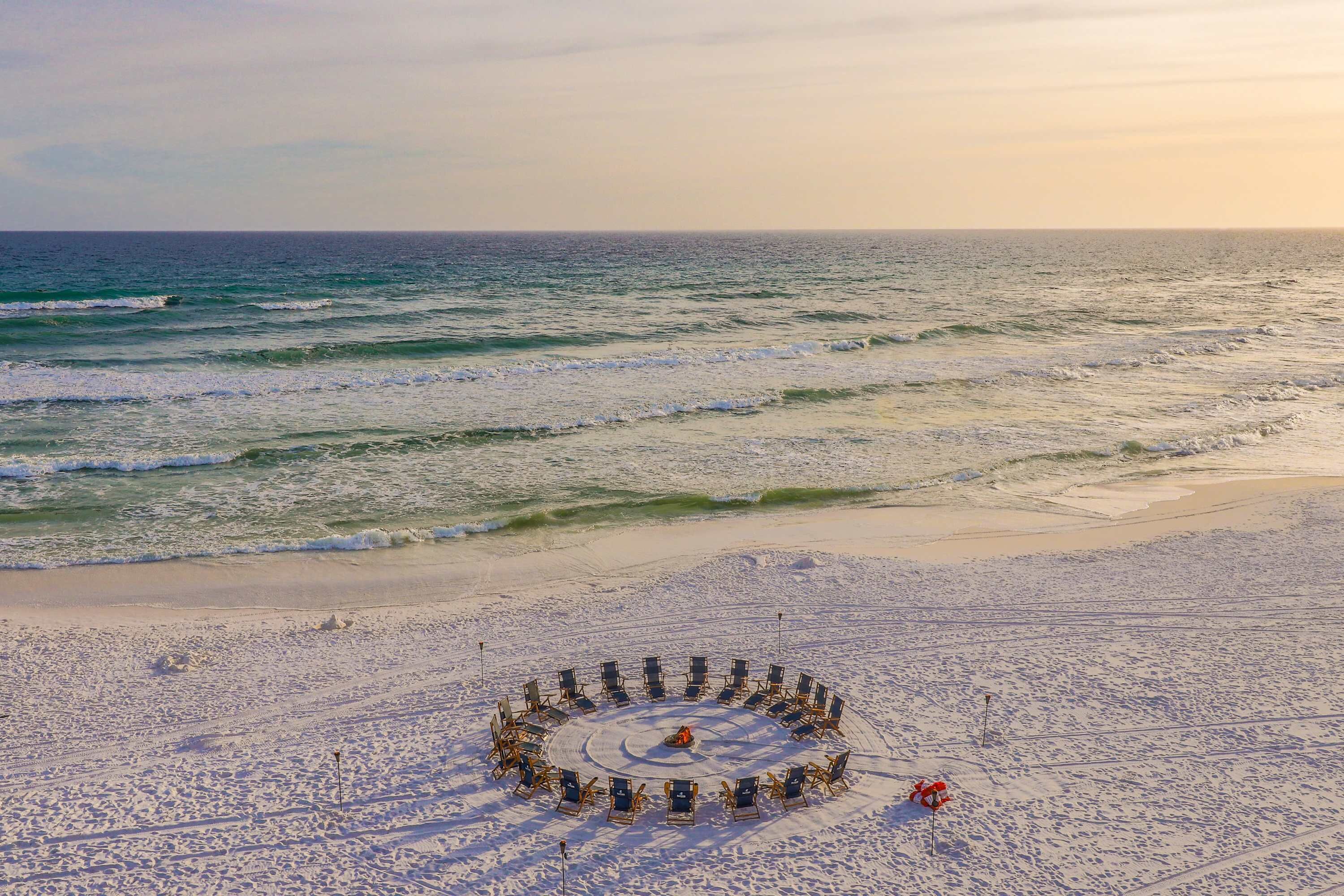 Ein Strand mit einer kreisförmigen Anordnung von Liegestühlen mit Blick auf den Ozean.
