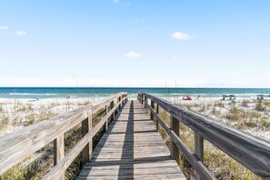A wooden boardwalk leading to a beach with clear skies and calm waters. - Cozy coastal condo with pool, fast WiFi, central AC, & easy beach access (Pensacola Beach)