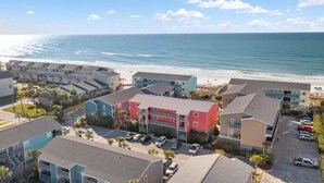 A coastal hotel with multiple buildings, a parking area, and a beach view. - Cozy coastal condo with pool, fast WiFi, central AC, & easy beach access (Pensacola Beach)