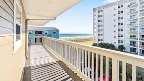 A balcony with a view of the beach and ocean, a building with multiple floors, and a clear sky. - Cozy coastal condo with pool, fast WiFi, central AC, & easy beach access (Pensacola Beach)