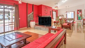 Een ruime woonkamer met een grote televisie, rode banken en een accentmuur van steen.