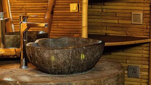 Un interior rústico de madera con un lavabo de piedra, bombillas colgantes y techo de madera.