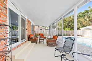 A covered patio with wicker furniture and a pool in the background. - Dog-Friendly Home with Private Pool & High-Speed WiFi - Near Beach & Boat Launch (Gulf Breeze)
