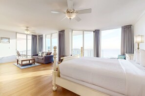 A spacious hotel room with a large bed, a ceiling fan, a balcony with a view, and a seating area with a coffee table and sofa. - Gorgeous penthouse w shared outdoor pool, hot tub, tennis - Snowbird-friendly (Destin)