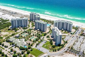 A high-rise hotel complex with multiple buildings, a beach, and a parking area. - Gorgeous penthouse w shared outdoor pool, hot tub, tennis - Snowbird-friendly (Destin)