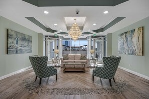 A spacious lobby with a central seating area, a chandelier, and artwork on the walls. - Gorgeous penthouse w shared outdoor pool, hot tub, tennis - Snowbird-friendly (Destin)