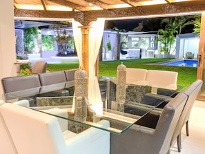 A modern outdoor seating area with a glass table, white sofas, and decorative lanterns. - In der Nähe des Strandes, beheiztes Schwimmbad, Spielraum, Spielzimmer, etc by Interhome (Marbella)