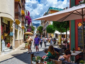 A bustling street with outdoor seating, shops, and a restaurant sign. - In der Nähe des Strandes, beheiztes Schwimmbad, Spielraum, Spielzimmer, etc by Interhome (Marbella)