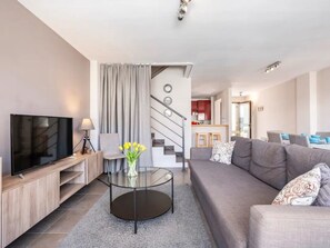 A modern living room with a flat-screen TV, a glass coffee table, a grey sofa, and a staircase leading to a kitchen. - "Casa Valle Niza" mit Pool by Interhome (Almayate Bajo)