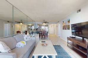 A spacious living area with a sofa, coffee table, TV, and dining area. - 11th Floor Condo, On-site restaurant, Multiple pools, hot tub, w splash pad (Destin)