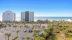 Un hotel sulla costa con un parcheggio, palme e vista sull'oceano.