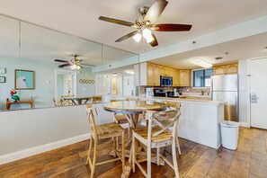 Une cuisine moderne avec des meubles en bois, un îlot central et un ventilateur de plafond.