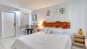 Ein Hotelzimmer mit Bett, Schreibtisch, Stuhl, Nachttisch und Wandbild.