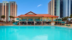 Ett hotell med en swimmingpool, flera balkonger och en byggnad med rött tak.