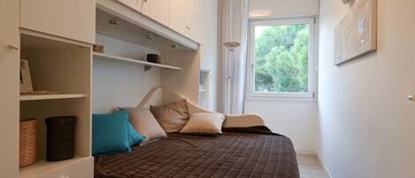 Un dormitorio con cama, armario empotrado y ventana con vistas a zonas verdes.