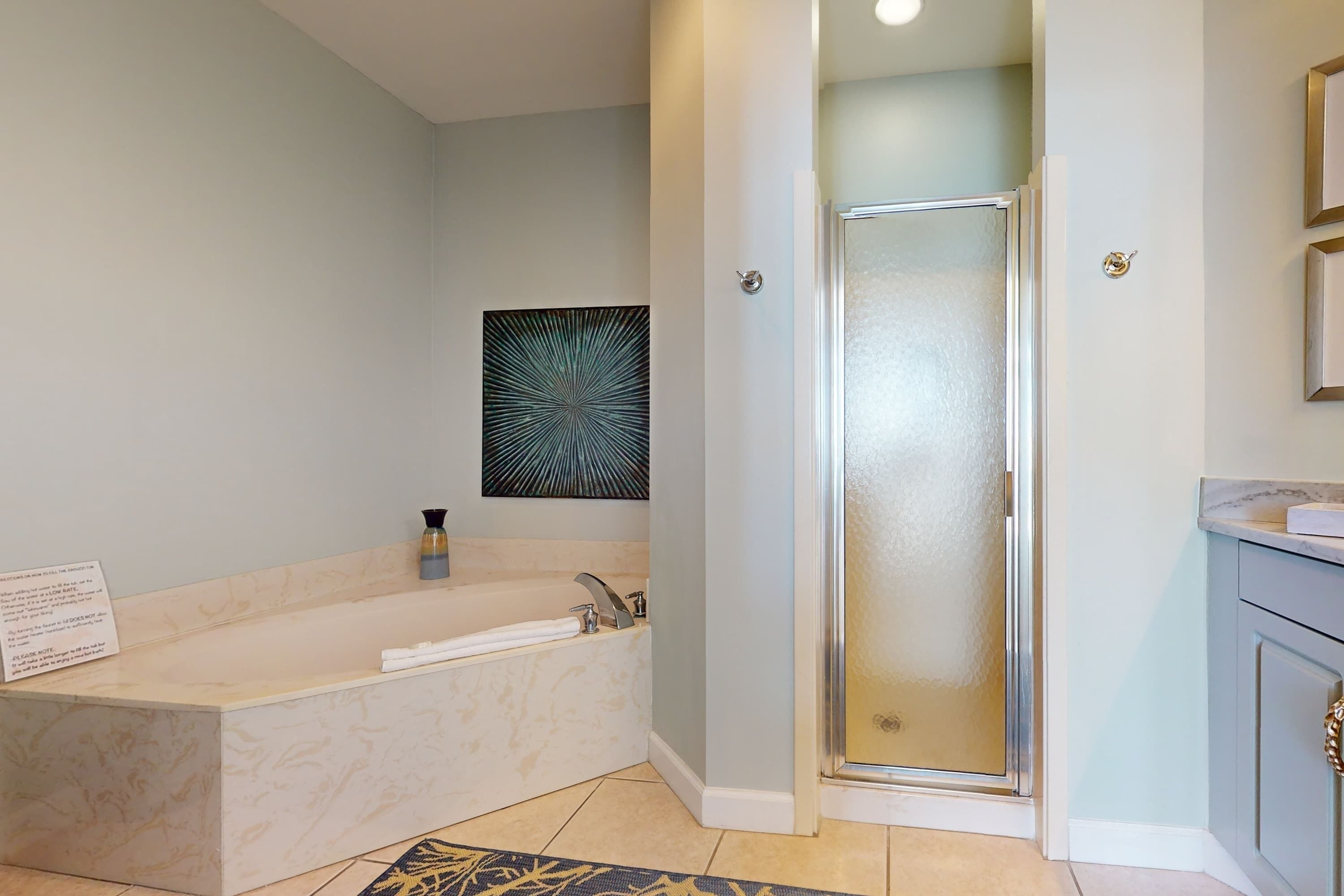 Un baño moderno con una bañera independiente, cabina de ducha de vidrio y encimera de mármol.