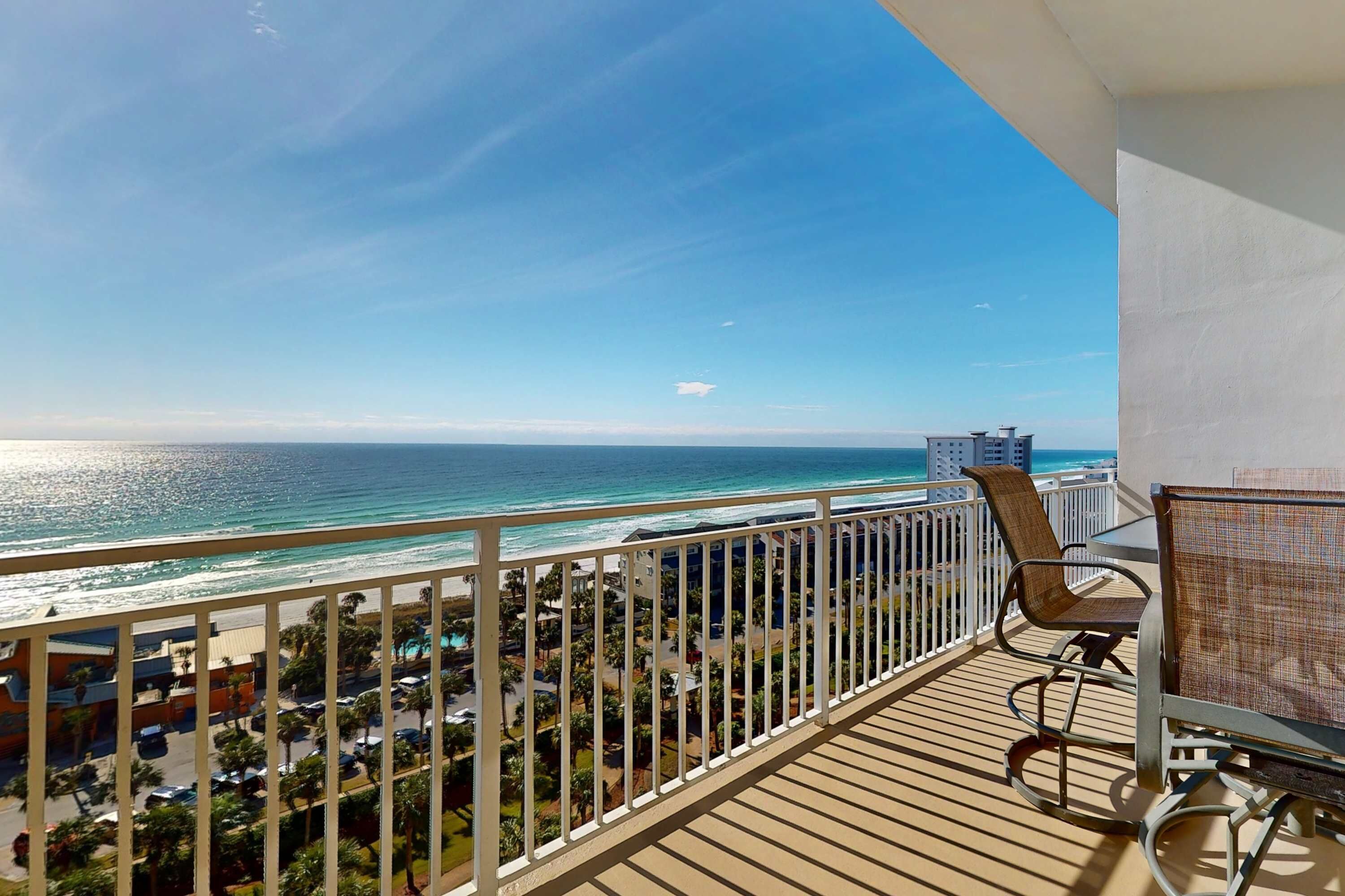 A balcony with a view of the ocean and a cityscape.