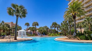A swimming pool surrounded by palm trees and a multi-story building. - Oceanfront 10th-floor condo with great view, balcony, WiFi, AC, & WD (Destin)