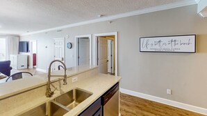 A kitchen with a double sink, a dishwasher, and a wall-mounted clock. - Oceanfront condo with scenic balcony, resort amenities, central AC, & W/D (Panama City Beach)