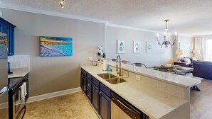 A modern kitchen with a large island, built-in oven, and a dining area with a chandelier. - Oceanfront condo with scenic balcony, resort amenities, central AC, & W/D (Panama City Beach)