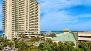 A tall hotel with multiple balconies, a green-roofed building, and a view of the ocean. - Colorful oceanfront condo with Gulf views, on-site pools & hot tub (Panama City Beach)