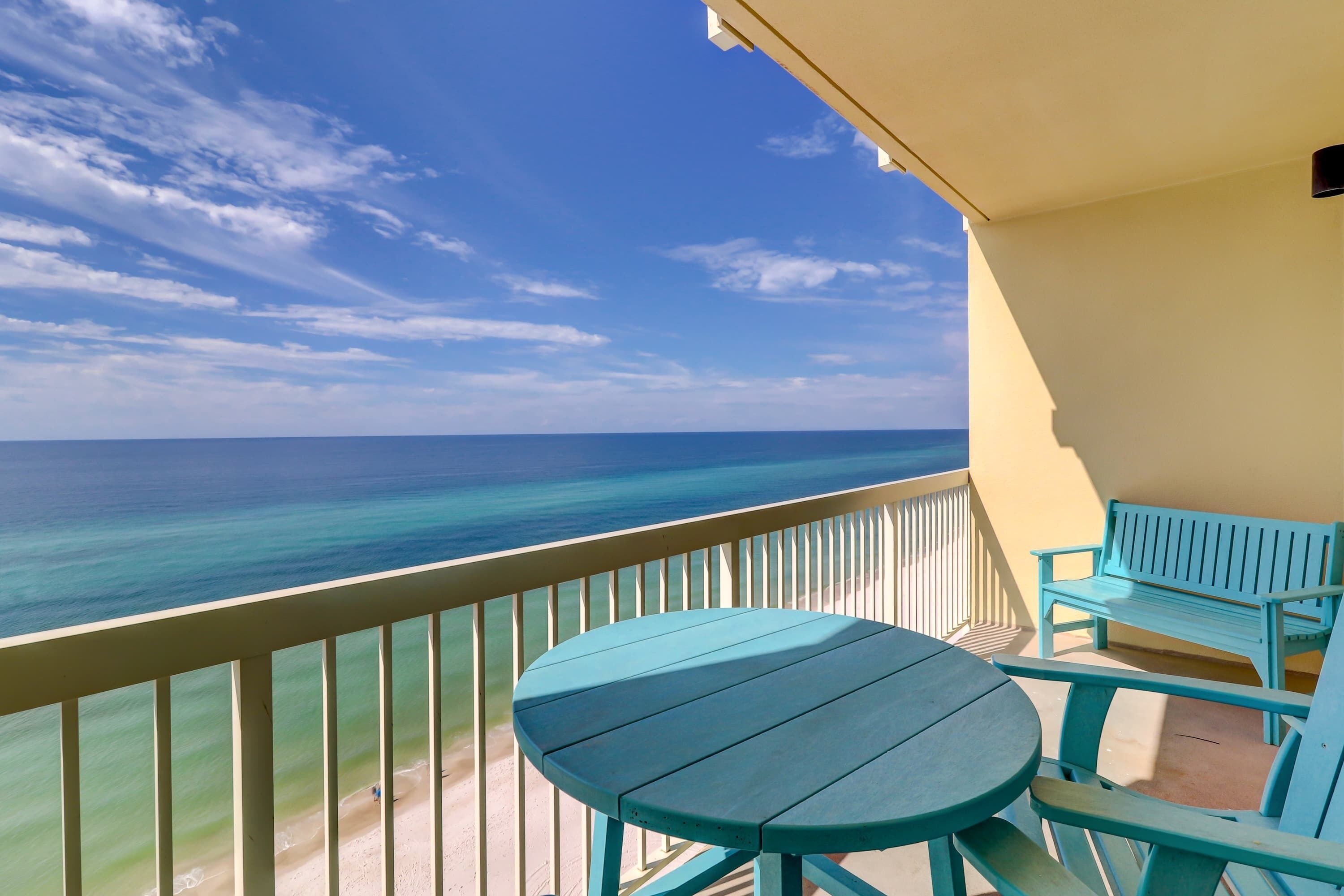 Een balkon met uitzicht op de oceaan, een tafel en twee stoelen.