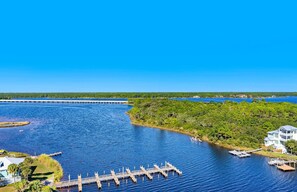 A waterfront property with a dock, a large house, and a forested area. - Oceanfront penthouse with pools, sauna, beach access & breathtaking ocean views (Panama City Beach)