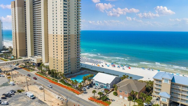 Un hotel de gran altura con vista a la playa, una piscina y un estacionamiento.