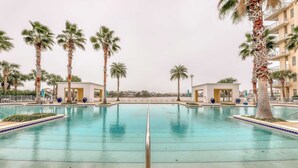 Ein großer, klarer Pool, umgeben von Palmen und kleinen Gebäuden.