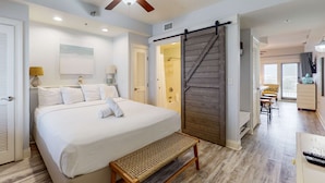 Ein Schlafzimmer mit Bett, einer Bank, Deckenventilator und einer Schiebetür im Bauernhausstil.