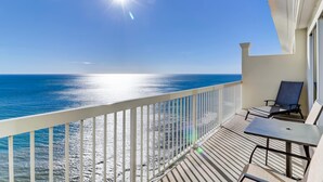 Uma varanda com vista para o oceano, uma mesa e duas cadeiras.