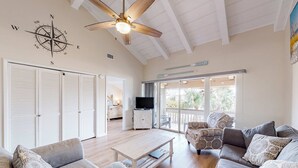 Un salon spacieux doté d’un ventilateur de plafond, d’une grande fenêtre et d’un téléviseur.
