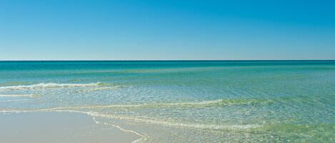 A beach with clear turquoise water and a sandy shore.