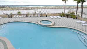Uma área de piscina com hidromassagem, espreguiçadeiras e vista para a praia.