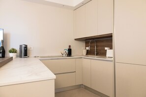 A modern kitchen with a marble countertop, built-in cabinets, and a wooden shelf. - Le Vele by Case al lago (Desenzano del Garda)