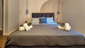 Ein modernes Schlafzimmer mit einem großen Bett, zwei Nachttischlampen und einem außergewöhnlichen Deckengestalt.