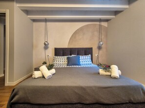 A modern bedroom with a large bed, two bedside lamps, and a unique ceiling design. - Le Vele by Case al lago (Desenzano del Garda)