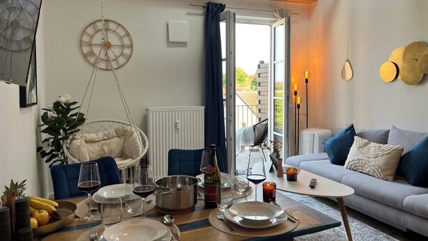 Een eethoek met een tafel gedekt voor twee personen, een hangstoel, een bank en uitzicht op de omgeving.