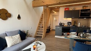 Een moderne woonkamer met een grijze bank, een witte salontafel en een trap naar een verdieping.