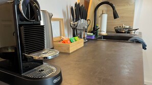 Een keuken met een zwarte koffiemachine, een houten doos met kleurrijke spullen, en een spoelbak met een kraan.