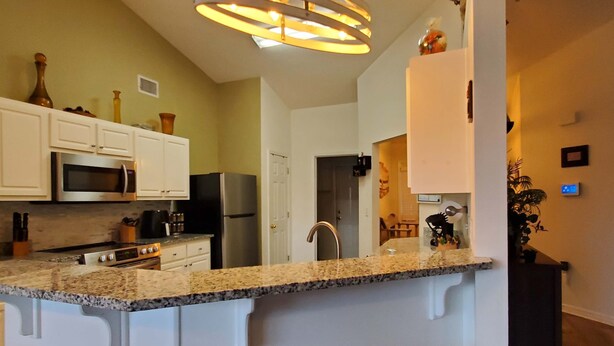 A modern kitchen with white cabinets, granite countertops, stainless steel appliances, and a central island. - Private home near the beach with washer and dryer and free Wifi (Navarre)