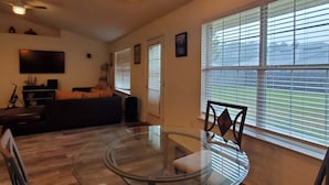 A modern living room with a glass-top dining table, a sofa, and a TV mounted on the wall. - Private home near the beach with washer and dryer and free Wifi (Navarre)