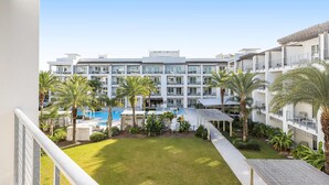 Un hotel con piscina, palmeras y un césped bien cuidado.