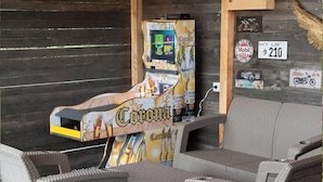 A Corona-branded arcade machine, wicker furniture, and a wall with various stickers and a license plate. - Dome with Private Jacuzzi in Villa de Leyva - Nature & Relaxation (Boyacá)