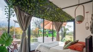 A bedroom with a bed, curtains, and a view of the outdoors. - Dome with Private Jacuzzi in Villa de Leyva - Nature & Relaxation (Boyacá)