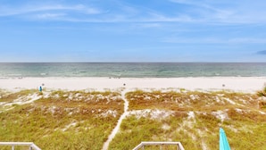 A beach with a clear sky, sandy shore, and grassy dunes. - Beachfront townhome with large deck & Gulf view - near Pier Park (Panama City Beach)