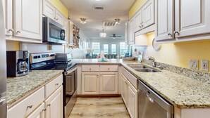 A kitchen with white cabinets, granite countertops, stainless steel appliances, and a central island. - Beachfront townhome with large deck & Gulf view - near Pier Park (Panama City Beach)