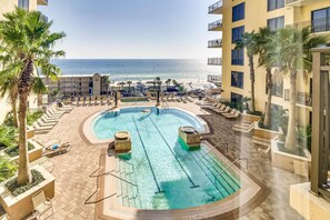 A pool area with a view of the beach, lounge chairs, and palm trees. - Sixth-floor condo with rooftop pool, Hot tub, high-speed WiFi & washer/dryer (Panama City Beach)